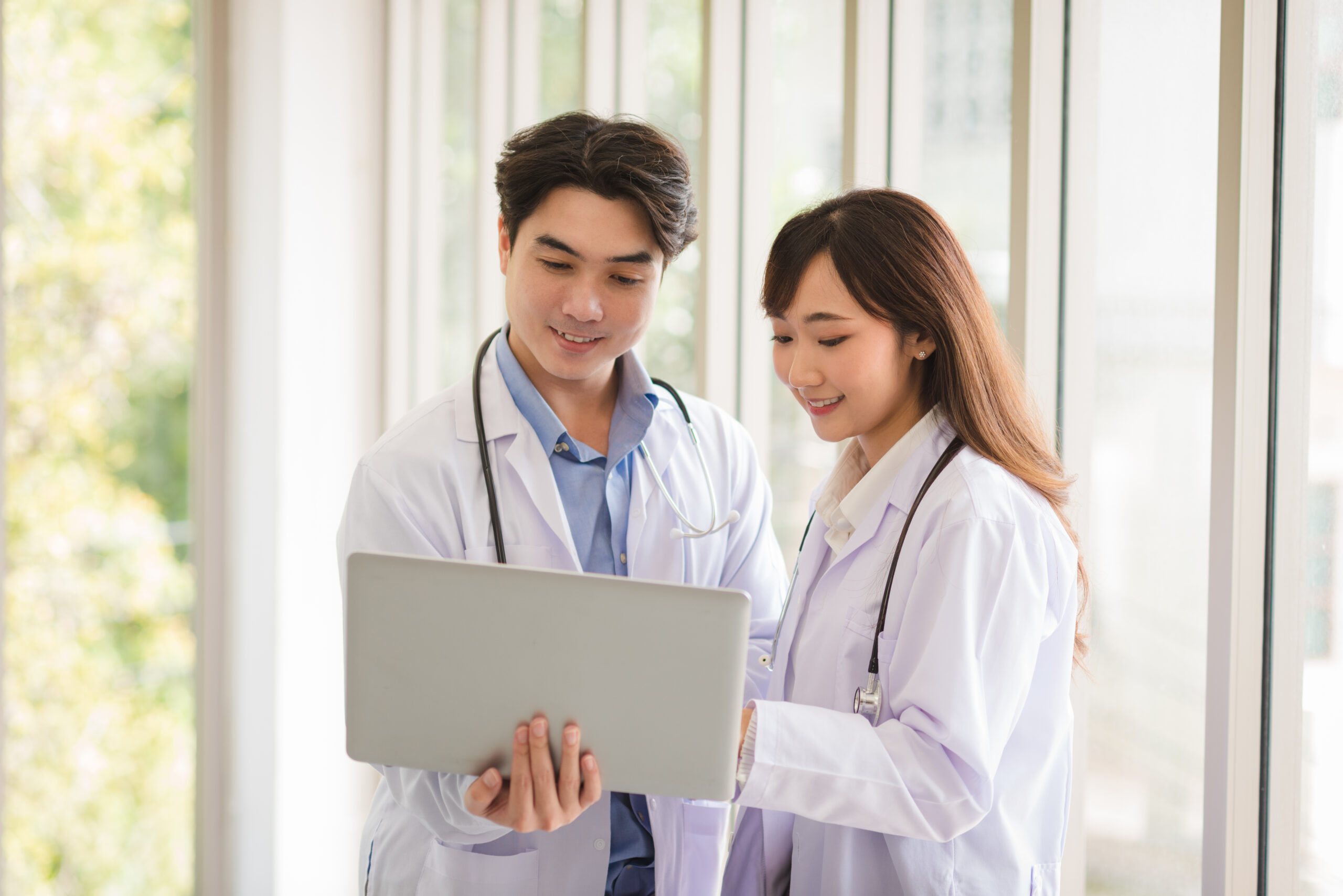 two asian doctors reading the phmc guidelines on a laptop